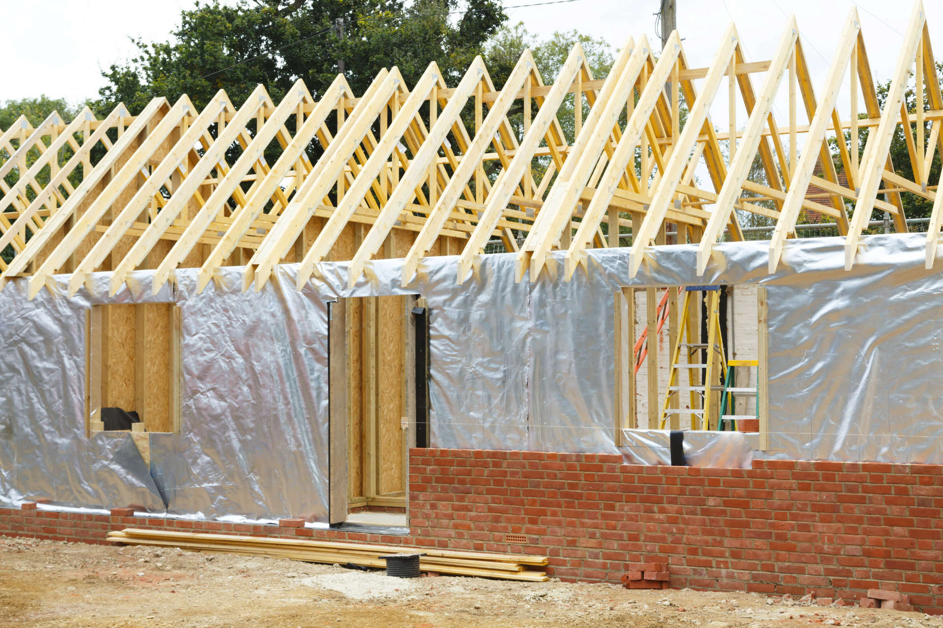 Timber frame house extension or annexe under construction with modern foil insulation and exterior brick wall